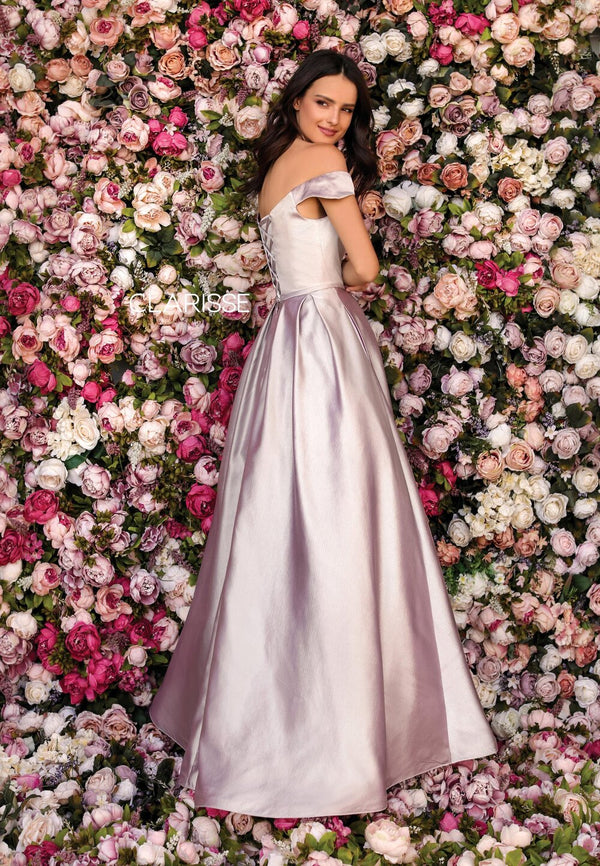 Clarisse 8010 is an off the shoulder ball gown prom dress with a self-fabric belt detail, roomy side pockets, and lace up back, made in shimmering mikado fabric.